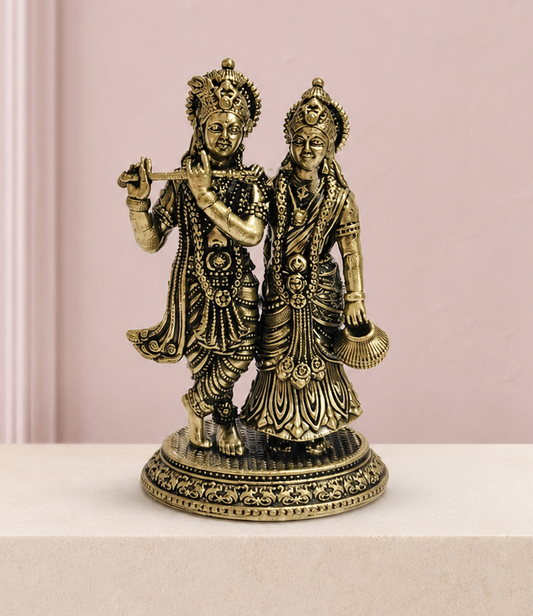 Radha Krishna Brass Idol on an ivory platform with a soft mauve heritage backdrop