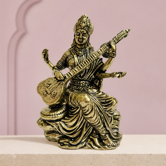 Saraswati Brass Idol with Veena on an ivory platform with a soft mauve heritage backdrop