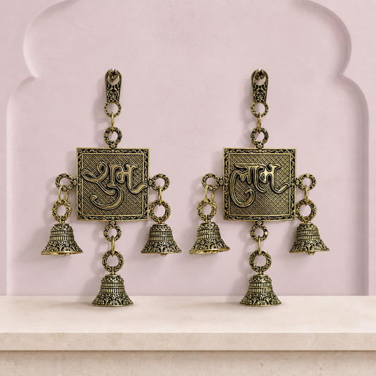 Shubh and Labh brass wall bell set displayed together on a soft mauve heritage wall