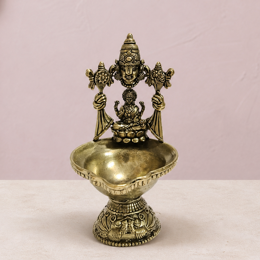 Venkateswara and Lakshmi Brass Diya Stand on an ivory platform with a soft mauve heritage backdrop